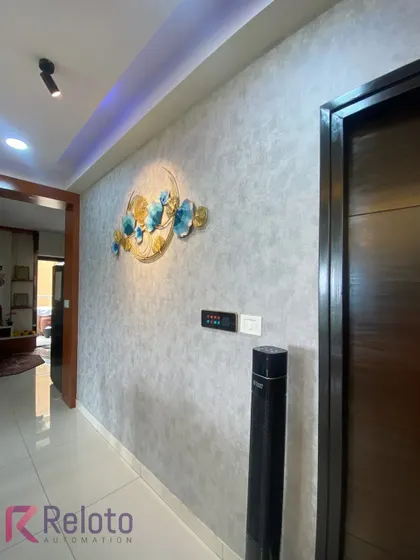 In this hallway, a multi-function Xeon touch panel is installed next to a smart tower fan and decorative wall art. This setup shows how we integrate control for lighting, climate, and other appliances into one convenient location.