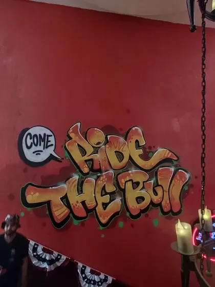"Come Ride The Bull" lettering in a classic graffiti bubble style, part of the larger commercial mural project for the cafe.