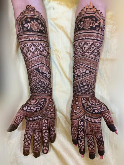 A symphony of art for a bride. This design is packed with traditional elements, including intricate jaali work and floral bands, creating a rich texture that covers the hands and arms completely.