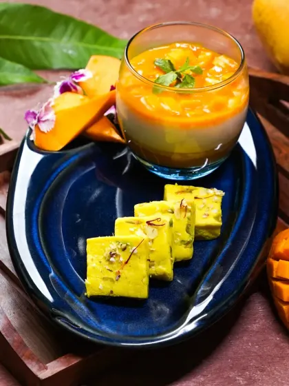 A modern take on Indian mango desserts, featuring a mango panna cotta and mango barfi on a vibrant blue plate. This shot beautifully blends traditional flavors with contemporary plating.