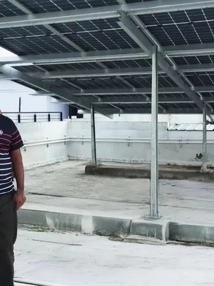 A resident stands under the newly installed solar panels at his housing society in Bangalore.