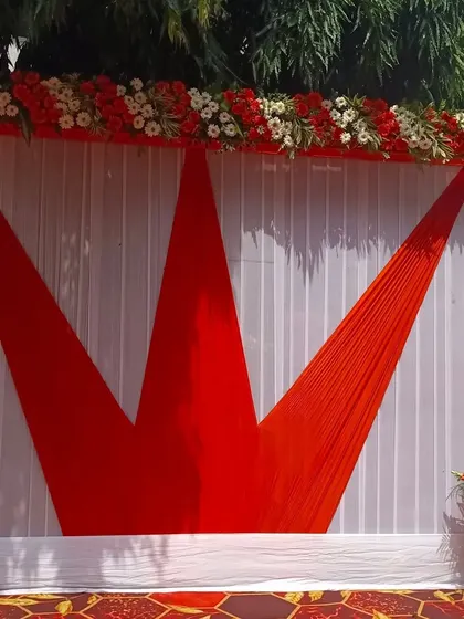I can create bold graphic designs with fabric. This backdrop features a crown-like pattern made with red fabric against a white pleated curtain, topped with a red and white floral border.
