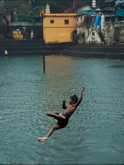 Another angle of a boy diving into the Banganga Tank, his body arched in a moment of pure freedom and fun.