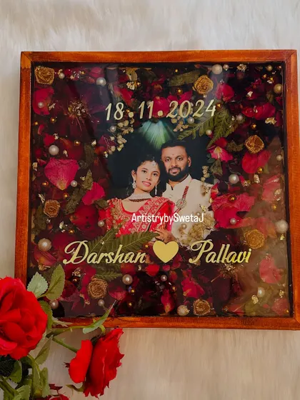 This varmala preservation frame is designed to be a centerpiece of love. The rich red flowers, combined with golden accents and a classic wooden frame, make it a truly special wedding memento.
