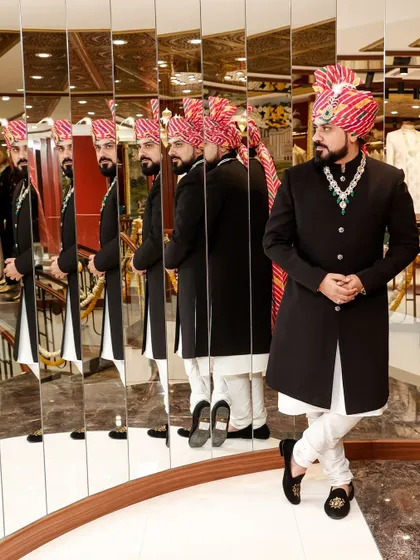The mirror reflects your light, so shine on. Here, a client looks regal in a classic black Bandhgala paired with a traditional Rajasthani safa, a look that commands attention.