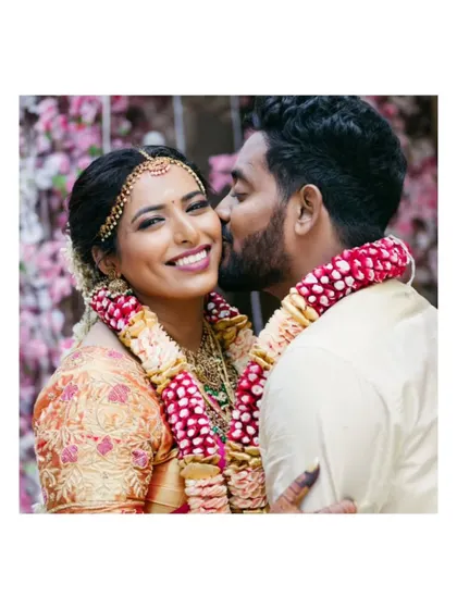 A sweet moment with the groom kissing the bride's cheek, capturing her joyful smile.