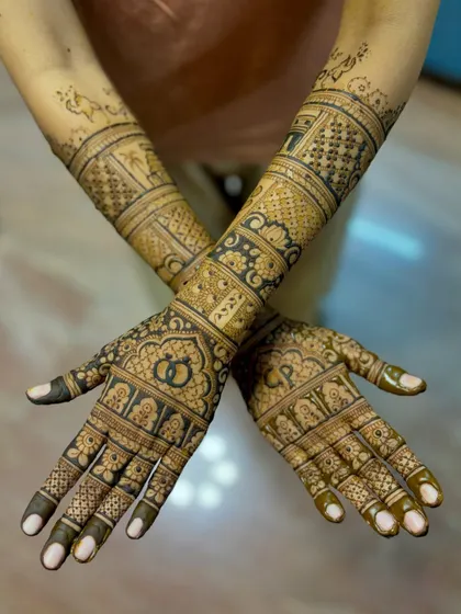 A crossed-hands view of the "CP" engagement mehendi, showing the full, intricate design.
