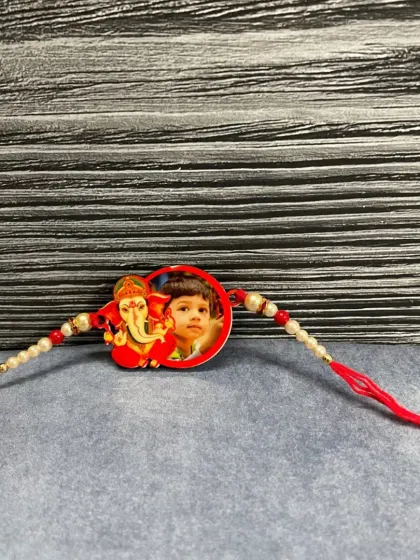 This custom rakhi combines a child's photo with an image of Lord Ganesha, making it a blessed and personal thread.