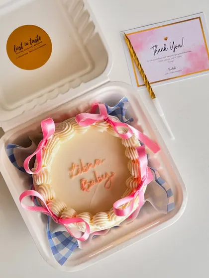 A cute "Libra Baby" bento cake. This mini cake features vintage-style piping and pink ribbons, all neatly packed in a personal-sized box.