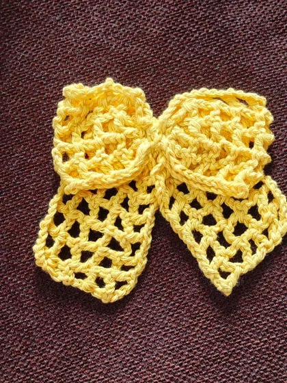 A beautiful, lacy crochet bow in a sunny yellow. The open stitch work gives it a light and airy feel, perfect for summer.