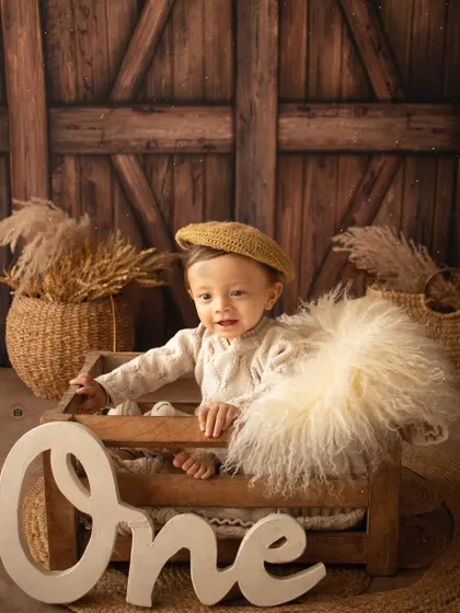This little boy, dressed in a cozy sweater and beret, smiles from a wooden crate next to a "One" sign.