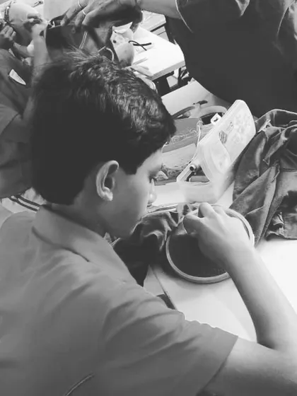 A black and white photo capturing a moment of focused learning at our cloth mending station.
