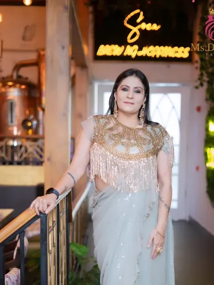 An outfit photoshoot with a model in a gorgeous fringed blouse and saree. The makeup is designed to complement the high-fashion look.
