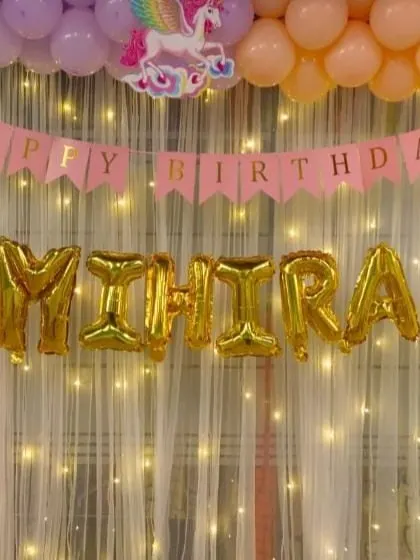 I brought a magical rainbow and unicorn theme to life for Mihira's birthday. This setup features a pastel rainbow balloon arch framing a shimmering backdrop with fairy lights. The gold foil letter balloons spelling out the name add a beautiful centerpiece for photos.
