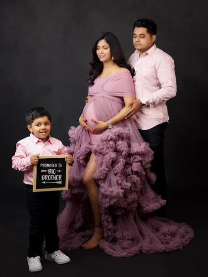 A creative and fun maternity announcement. The older brother-to-be proudly holds a sign, sharing the happy news in this stylish family studio session.