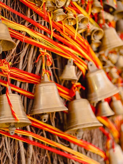 A detail of the tree trunk, made from natural twigs and adorned with hundreds of brass temple bells tied with sacred red and yellow threads.