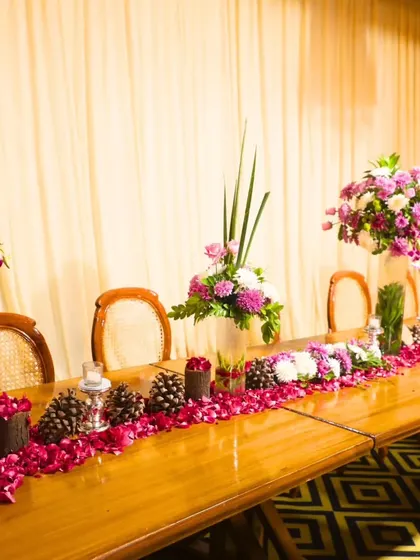 A beautifully decorated dining table with a runner of fresh flowers and pinecones. Our service includes creating stunning tablescapes that enhance the overall dining experience.