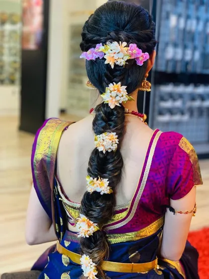 The back view of a South Indian bridal look, featuring a beautiful floral braid that complements the rich silk saree.