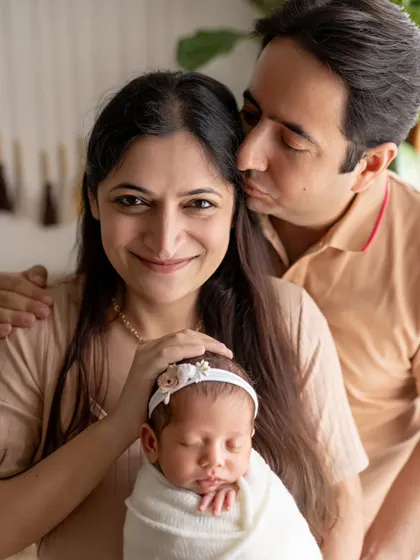 A father's gentle kiss for his wife as they both hold their precious newborn. This photo is a beautiful testament to their love and the new life they have created together.