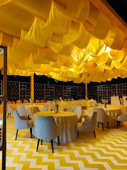 The seating area within the yellow-themed event, with modern grey chairs providing a stylish contrast to the vibrant floor and ceiling. The layout is designed for comfortable dining and socializing.