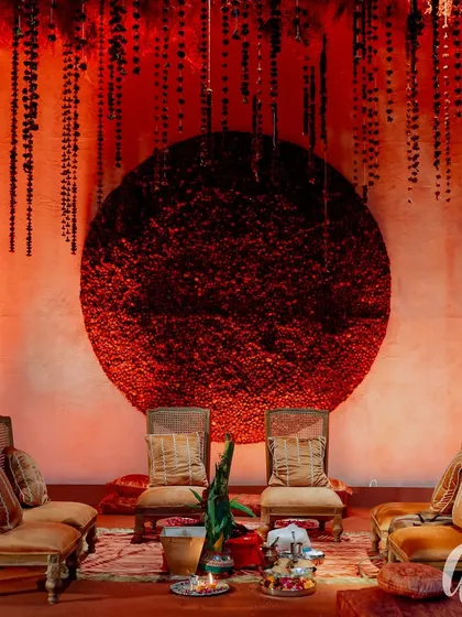 The main stage for the couple, featuring a massive circular backdrop made entirely of red flowers. The design is powerful and symbolic, framed by hanging floral strings for added texture.