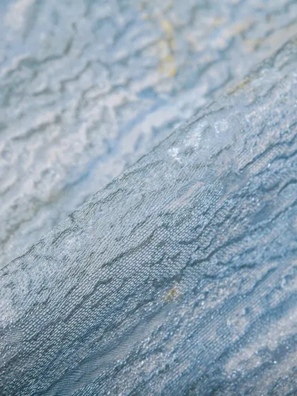 This light blue wallpaper has a beautiful, wrinkled texture that catches the light, creating a sense of movement and depth. It's a high-quality, exquisite design that can transform any home.