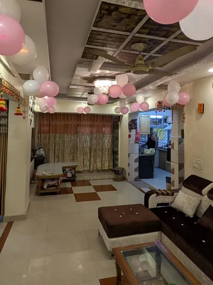 A living room filled with pink and white balloon clusters on the ceiling, creating a simple and festive atmosphere for a welcome home party.