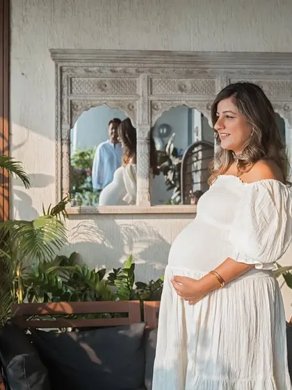 A quiet moment of reflection for the mother-to-be in her beautiful home. The mirror captures her partner in the background, adding a layer of storytelling to this lifestyle maternity portrait.