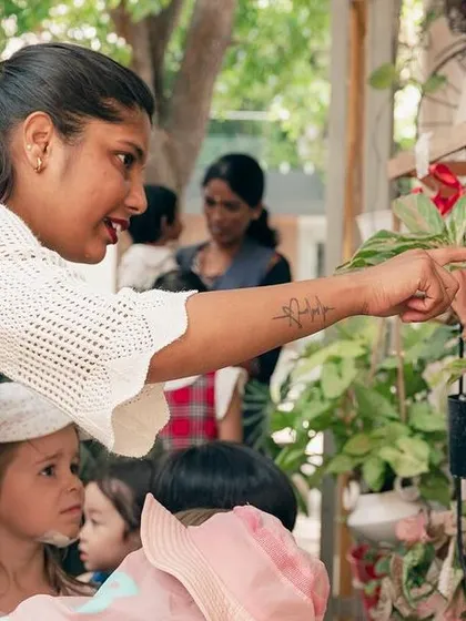 A teacher points out a specific plant to the children, engaging them in a discussion about what they see.