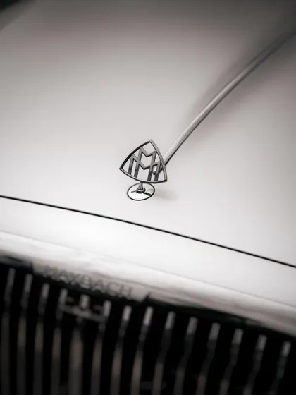 A black and white detail shot of the iconic Maybach hood ornament. This minimalist and elegant style of photography is ideal for highlighting the heritage and luxury associated with high-end automotive brands.