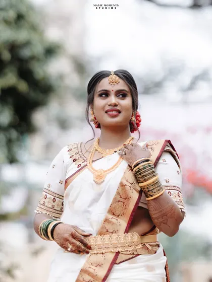 A classic bridal portrait of Sumitha. Her elegant white and red saree and traditional gold jewelry are beautifully highlighted.