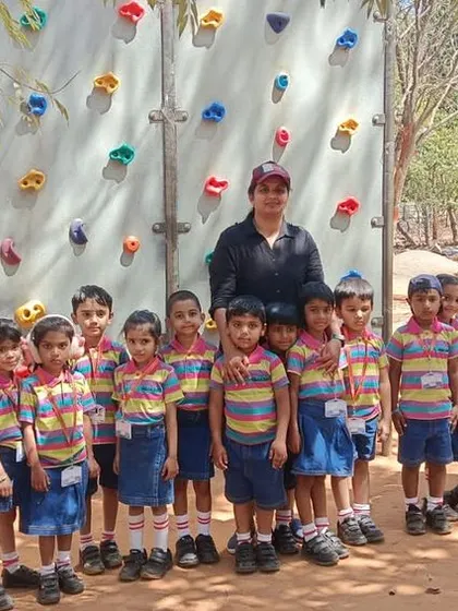 Students stand in front of the rock climbing wall at Jain Farm, ready for another adventure.