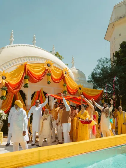 A wide shot of a Haldi ceremony, showing the beautiful yellow and orange decor and the lively participation of family and friends.
