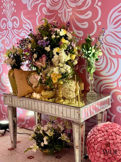 A cluster of beauty. We used mirrored console tables adorned with large floral arrangements and golden accessories to create stunning decorative corners.