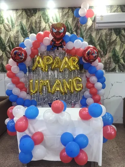 A clear view of the main birthday backdrop for a Spiderman party, featuring a balloon arch, foil name lettering, and a silver fringe curtain.