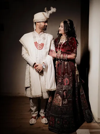 A stylish wedding day portrait of the couple. The groom has his arm around the bride as they look at each other, captured with dramatic lighting that creates a cinematic feel.