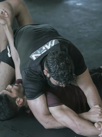 A close-up of a grappling exchange. The focus is on controlling the opponent's posture to set up a submission.