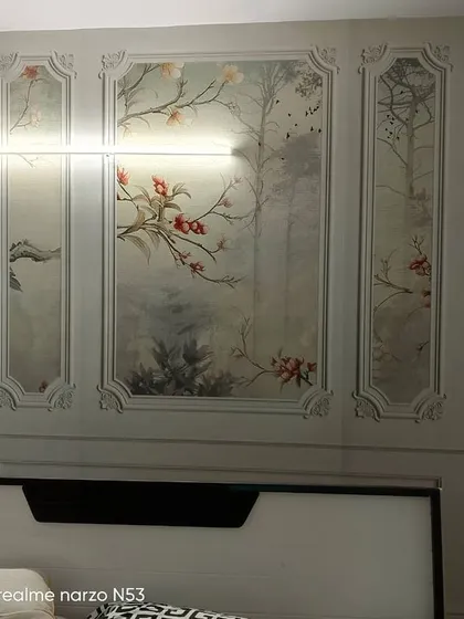 A direct view of the chinoiserie-style paneled wallpaper, highlighting the delicate tree and flower details.