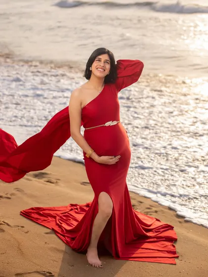 The golden light of sunrise makes this red gown glow. This portrait captures the strength and beauty of the mom-to-be as she enjoys a serene moment on the beach.