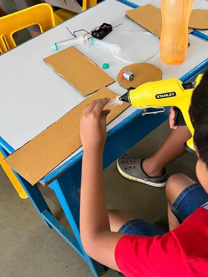 Another angle of a student constructing the disc brake model, showing their focus and engagement. We provide all the necessary tools, including glue guns and cutters, in a safe environment.