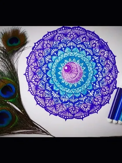 This mandala is an exploration of blue and purple hues, inspired by the colors of a peacock's feather. The design features layers of detailed patterns that radiate from a central point, creating a balanced and calming visual effect.