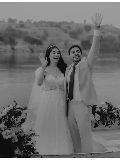 A romantic escape. The couple shares a quiet moment in a beautifully decorated boat, waving to their loved ones as they begin their journey together.