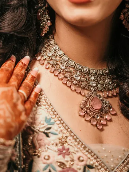 A detail shot focusing on the bride-to-be's exquisite necklace and henna-adorned hand. We love capturing the beautiful details that complete the bridal look.