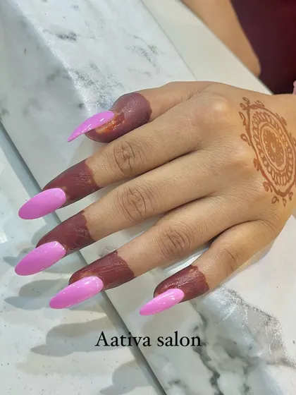 A popular combination for festive seasons is pairing mehendi with fresh nail art. This image shows a simple mandala mehendi on the back of the hand, perfectly complemented by long, bright pink stiletto nail extensions.