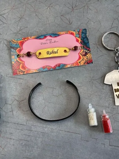 This Rakhi combo includes a personalized Park Avenue perfume, a custom jersey-shaped keychain, a name-engraved Rudraksh rakhi, and a stylish half-kada bracelet in black.