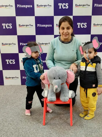 Introducing the letter 'E' with an elephant theme. Our little ones, wearing elephant ear art, pose with their teacher and a stuffed elephant, making learning alphabets a fun affair.