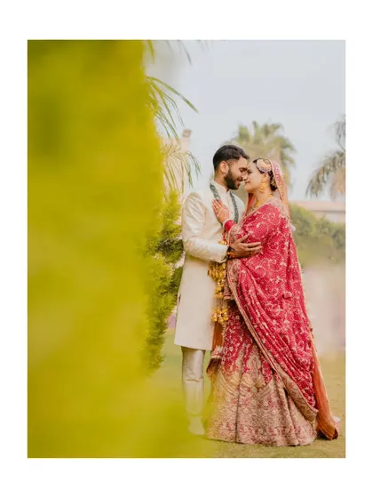A romantic and artistic shot of the couple, framed by lush greenery. This photo from their wedding day feels intimate and cinematic.