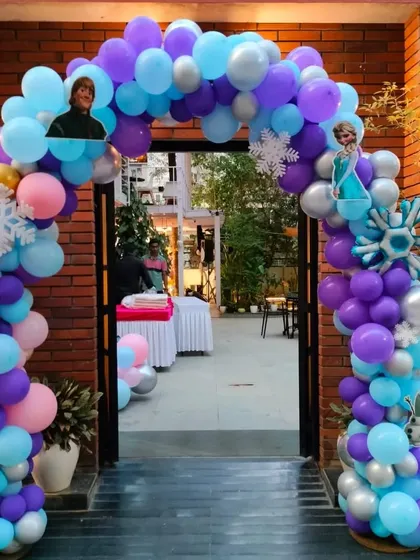 A balloon arch at the entrance to the Frozen party, decorated with character images and snowflake cutouts.