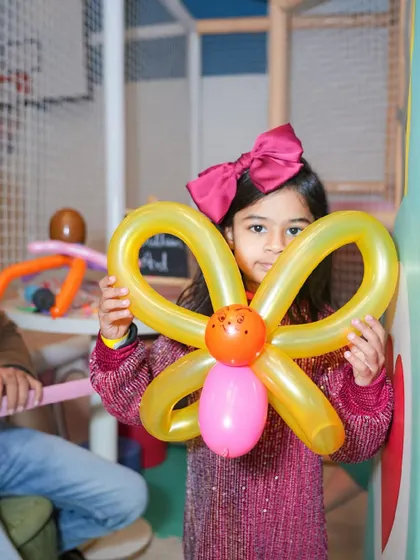 A girl holds up a butterfly made from twisted balloons, created by our talented balloon artist.