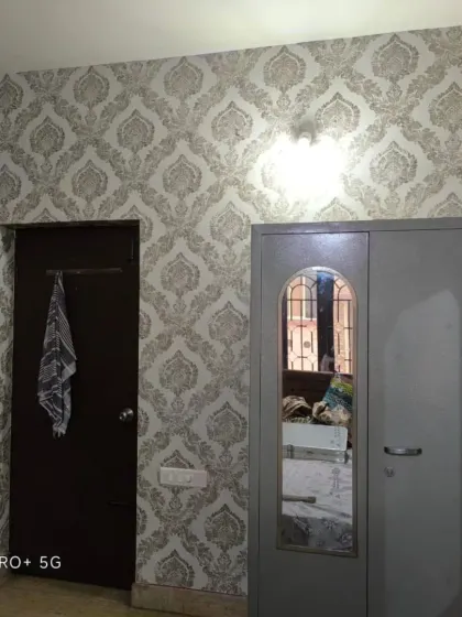 A bedroom with two different wallpapers: a textured design and a classic grey damask pattern.